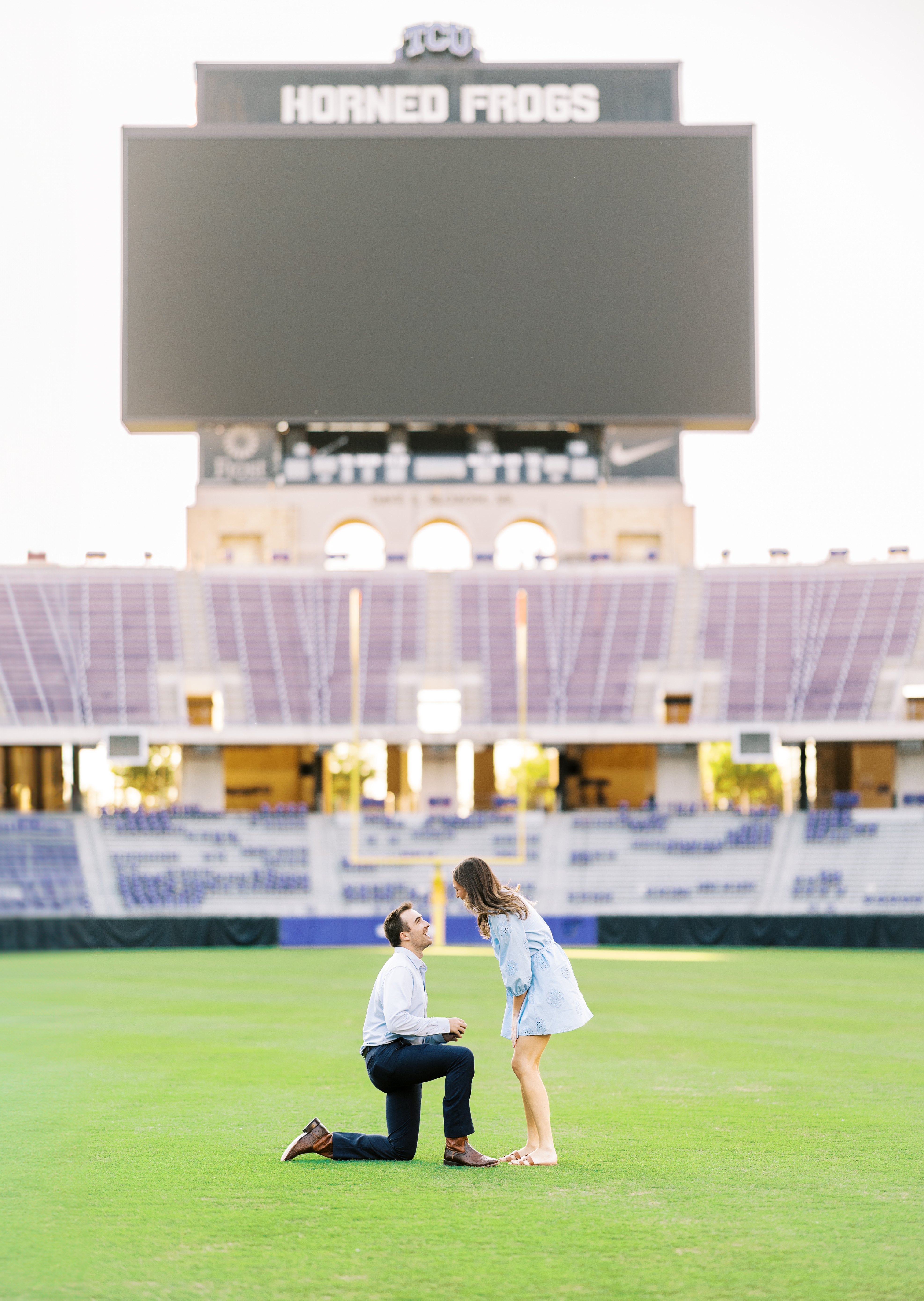 Spencer proposes to Samantha on the TCU football field at sunset, with joyful laughter and surprise captured in the moment.