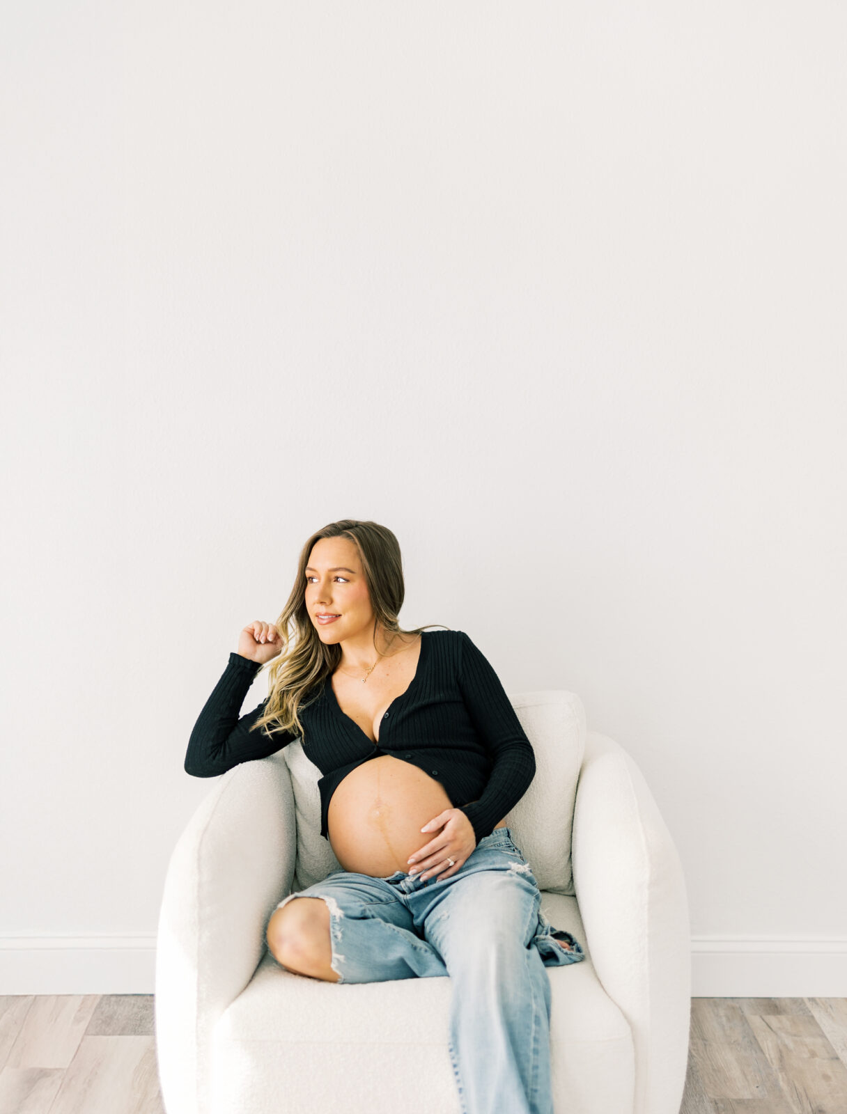Expecting mother seated during maternity photoshoot in Dallas studio