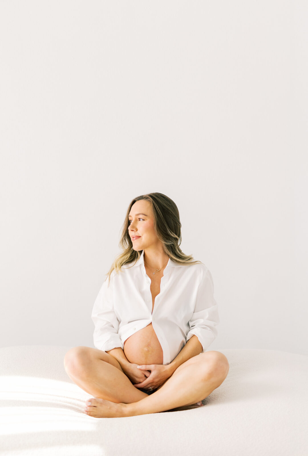 Expecting mother in Dallas holding baby bump during maternity photoshoot
