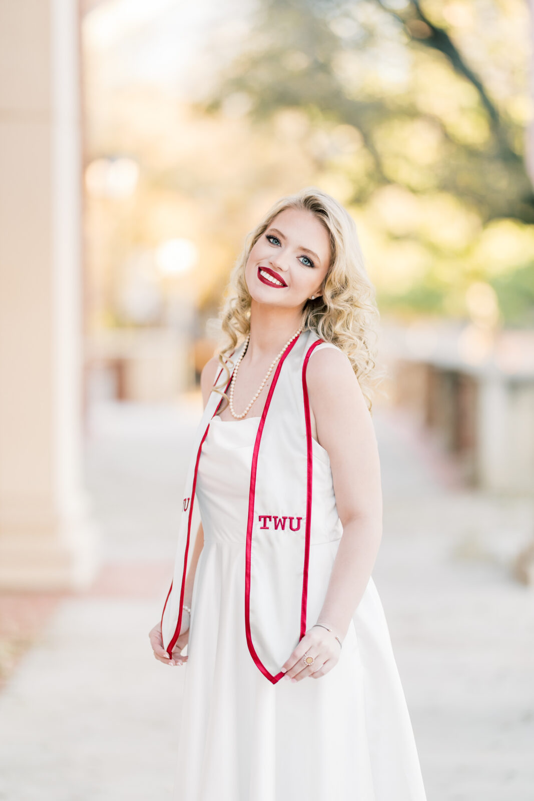 very poses in her white dress at the Texas Woman’s University Student Union.