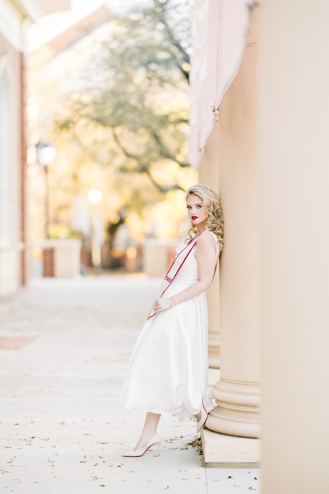 very poses in her white dress at the Texas Woman’s University Student Union.
