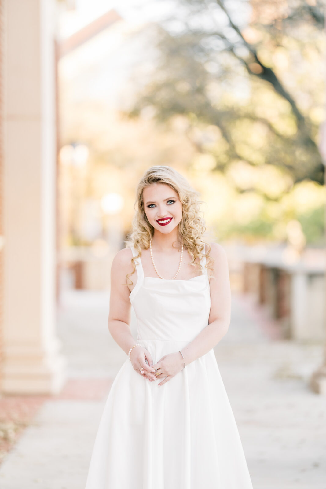 very poses in her white dress at the Texas Woman’s University Student Union.