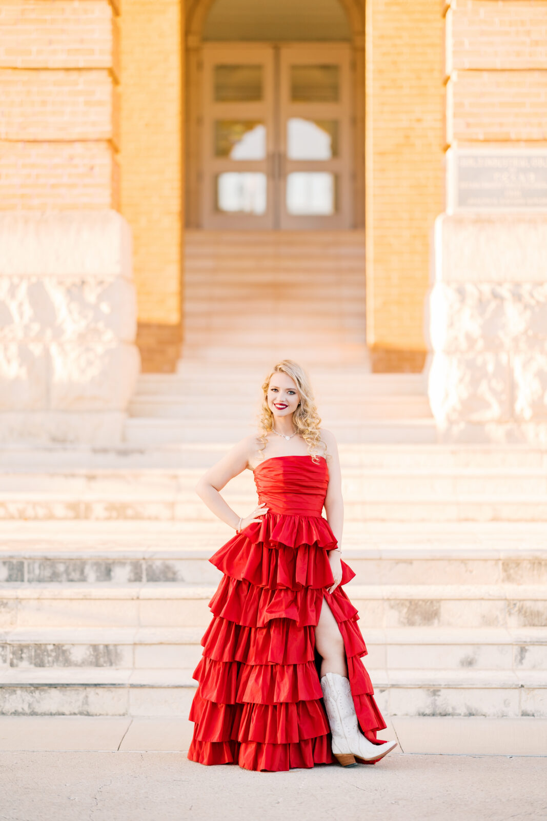 Avery in a red ballgown and cowgirl boots at Old Main for her TWU graduation portraits.