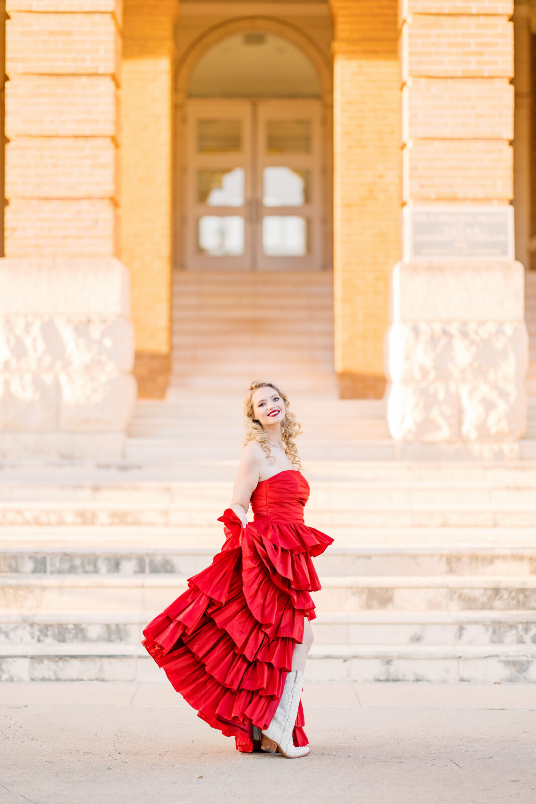 Avery in a red ballgown and cowgirl boots at Old Main for her TWU graduation portraits.