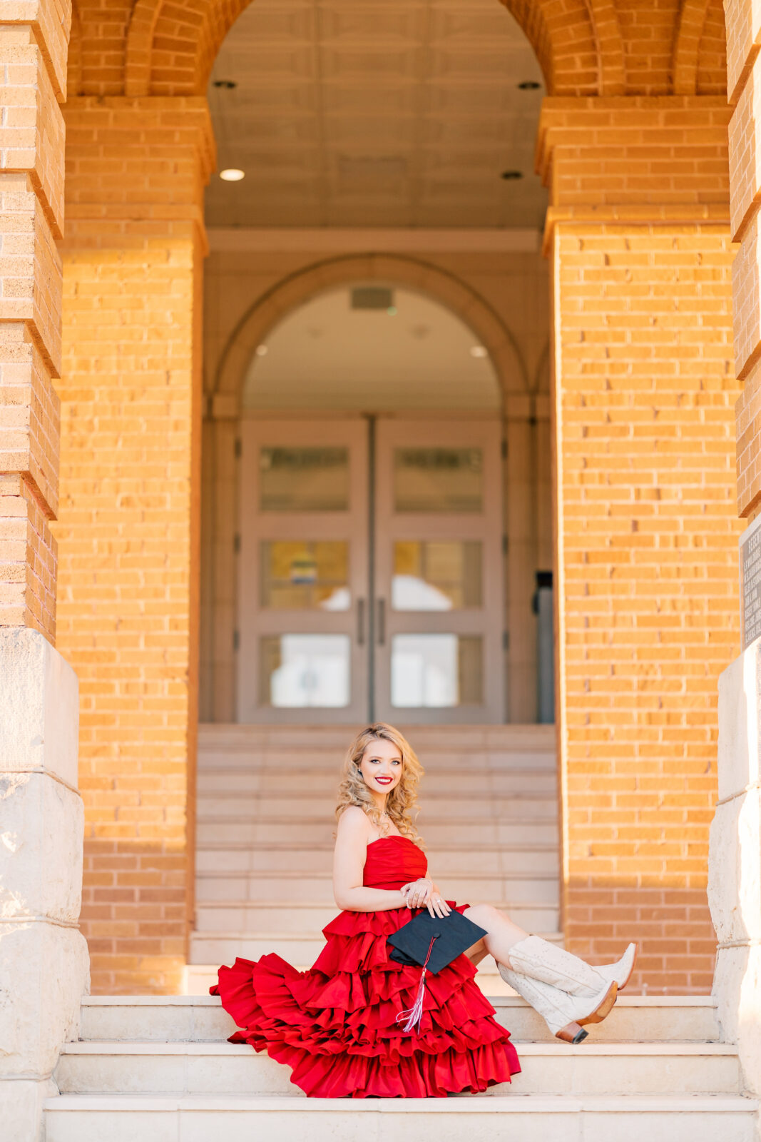 Avery in a red ballgown and cowgirl boots at Old Main for her TWU graduation portraits.
